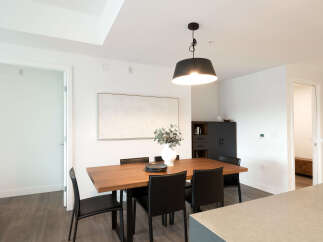 This modern dining room features a sleek wooden table with black chairs, illuminated by a stylish pendant light.