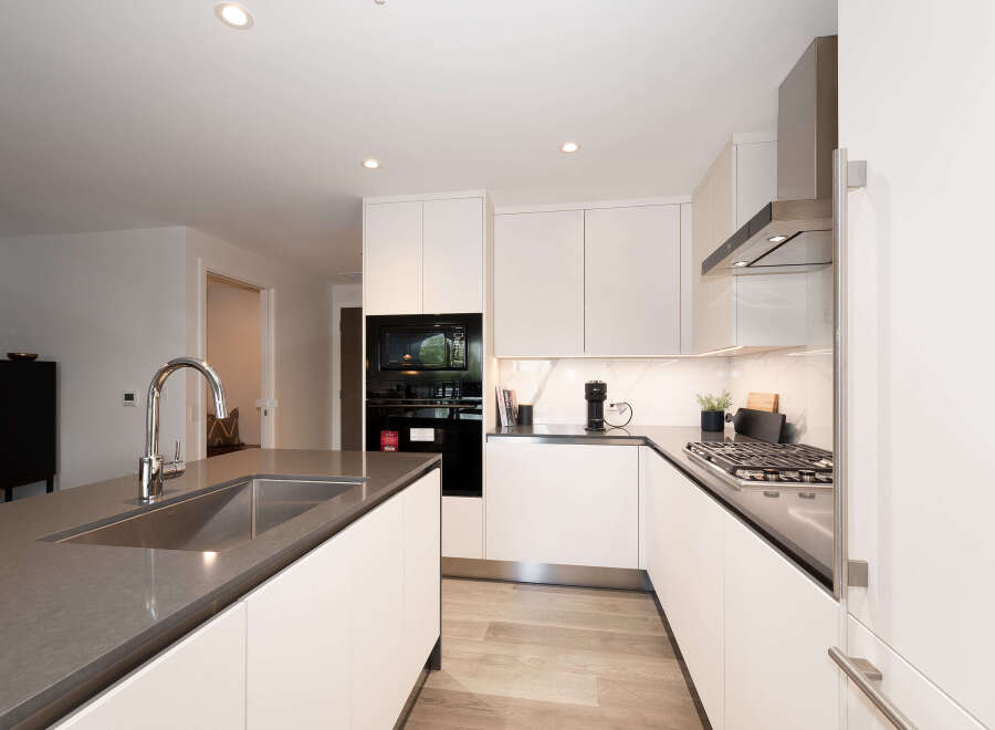 Experience modern luxury in this stunning kitchen, featuring sleek white cabinetry and a spacious island with a built-in sink and chrome faucet.