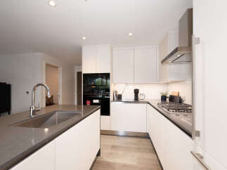 Experience modern luxury in this stunning kitchen, featuring sleek white cabinetry and a spacious island with a built-in sink and chrome faucet.