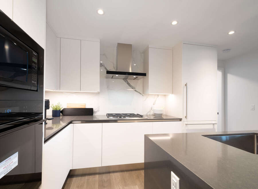Experience modern luxury in this stunning kitchen, featuring sleek white cabinetry and a striking marble backsplash.