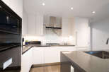 Experience modern luxury in this stunning kitchen, featuring sleek white cabinetry and a striking marble backsplash.
