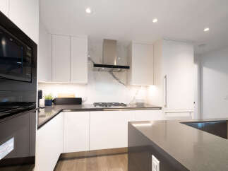 Experience modern luxury in this stunning kitchen, featuring sleek white cabinetry and a striking marble backsplash.