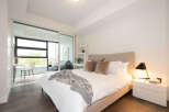 Experience modern living in this beautifully appointed bedroom, featuring a plush king-sized bed with luxurious linens and a stylish upholstered headboard.