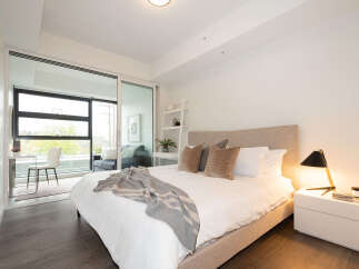 Experience modern living in this beautifully appointed bedroom, featuring a plush king-sized bed with luxurious linens and a stylish upholstered headboard.