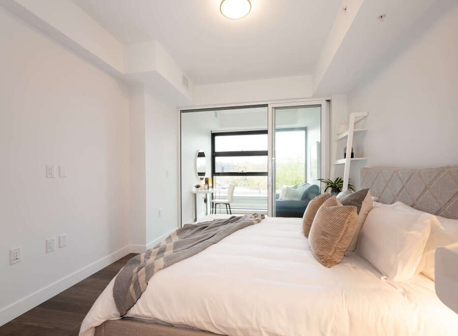 Experience modern comfort in this beautifully appointed bedroom, featuring a plush bed with a diamond-tufted headboard and a cozy throw blanket.