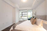 Experience modern comfort in this beautifully appointed bedroom, featuring a plush bed with a diamond-tufted headboard and a cozy throw blanket.