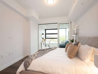 Experience modern comfort in this beautifully appointed bedroom, featuring a plush bed with a diamond-tufted headboard and a cozy throw blanket.