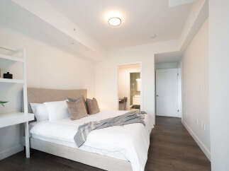 Experience modern comfort in this beautifully appointed bedroom, featuring a plush king-sized bed with crisp white linens and decorative throw pillows.