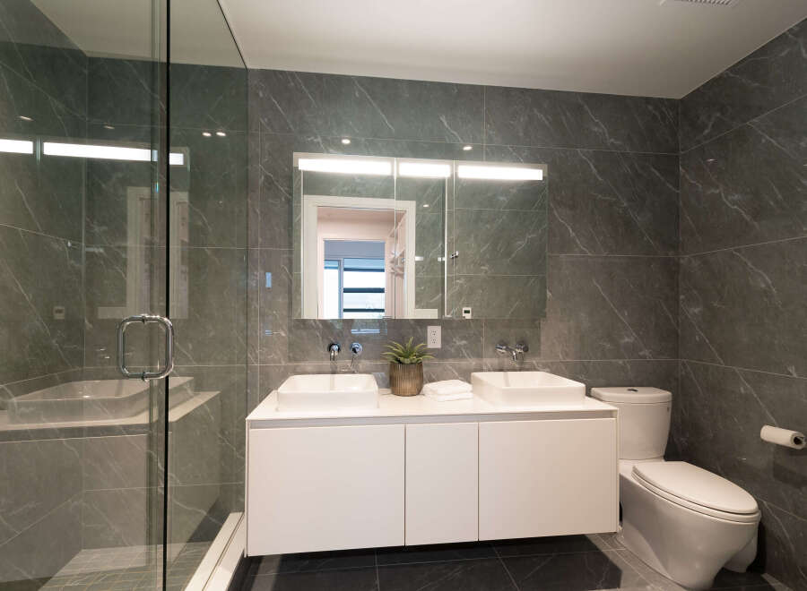 Experience modern luxury in this stunning bathroom, featuring a sleek double vanity with vessel sinks and a spacious glass-enclosed shower.
