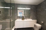 Experience modern luxury in this stunning bathroom, featuring a sleek double vanity with vessel sinks and a spacious glass-enclosed shower.