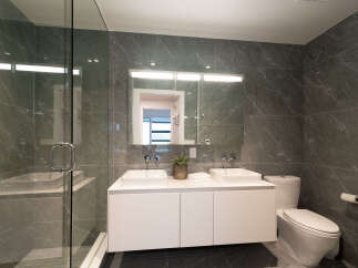 Experience modern luxury in this stunning bathroom, featuring a sleek double vanity with vessel sinks and a spacious glass-enclosed shower.