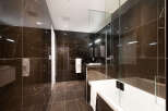 Experience luxury in this modern bathroom featuring sleek, dark marble tiles on the walls and floor.