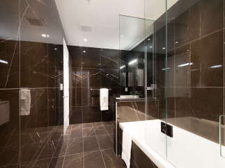 Experience luxury in this modern bathroom featuring sleek, dark marble tiles on the walls and floor.