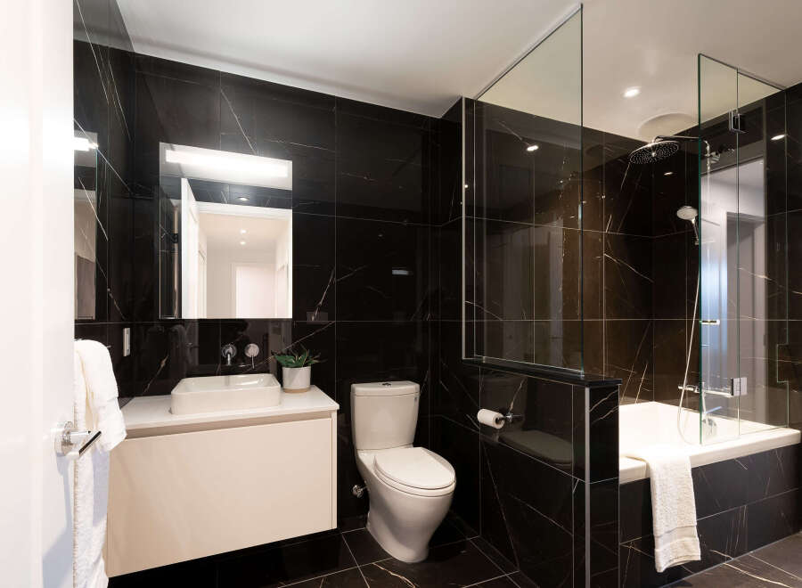 Experience modern luxury in this stunning bathroom featuring sleek black marble tiles and a floating vanity with a vessel sink.