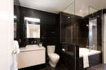 Experience modern luxury in this stunning bathroom featuring sleek black marble tiles and a floating vanity with a vessel sink.