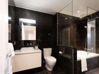 Experience modern luxury in this stunning bathroom featuring sleek black marble tiles and a floating vanity with a vessel sink.