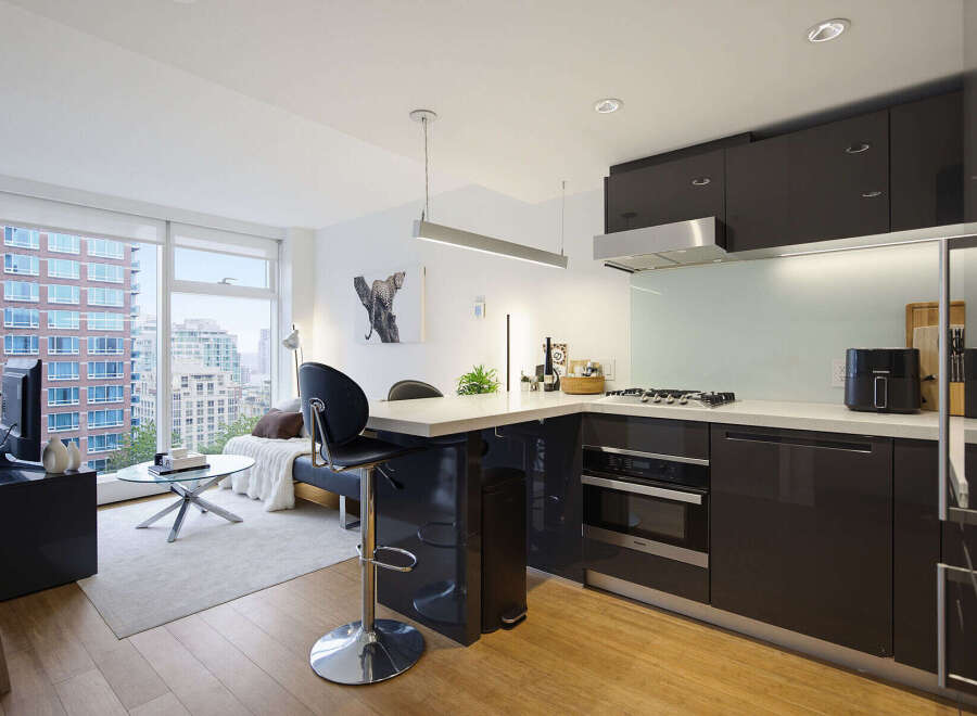 Experience modern urban living in this stylish studio apartment featuring a sleek, contemporary kitchen with dark cabinetry and stainless steel appliances.