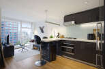 Experience modern urban living in this stylish studio apartment featuring a sleek, contemporary kitchen with dark cabinetry and stainless steel appliances.