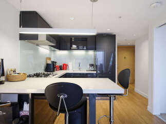 Experience modern urban living in this sleek kitchen, featuring high-gloss cabinetry and a stylish backsplash.