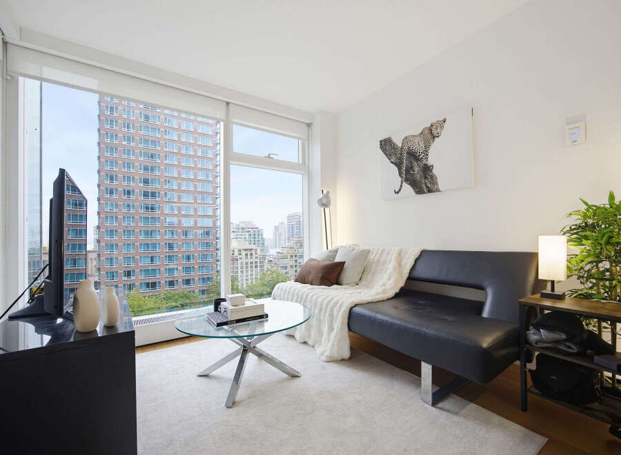 Experience modern city living in this stylish apartment featuring a sleek black sofa and a chic glass coffee table.