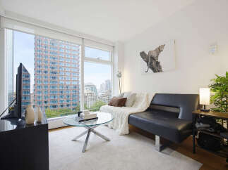 Experience modern city living in this stylish apartment featuring a sleek black sofa and a chic glass coffee table.