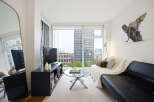Experience modern city living in this stylish apartment featuring a sleek black sofa adorned with a cozy cream throw and accent pillows.