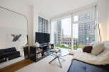 Experience modern urban living in this stylish apartment featuring a sleek black sofa complemented by a plush white throw and accent pillows.