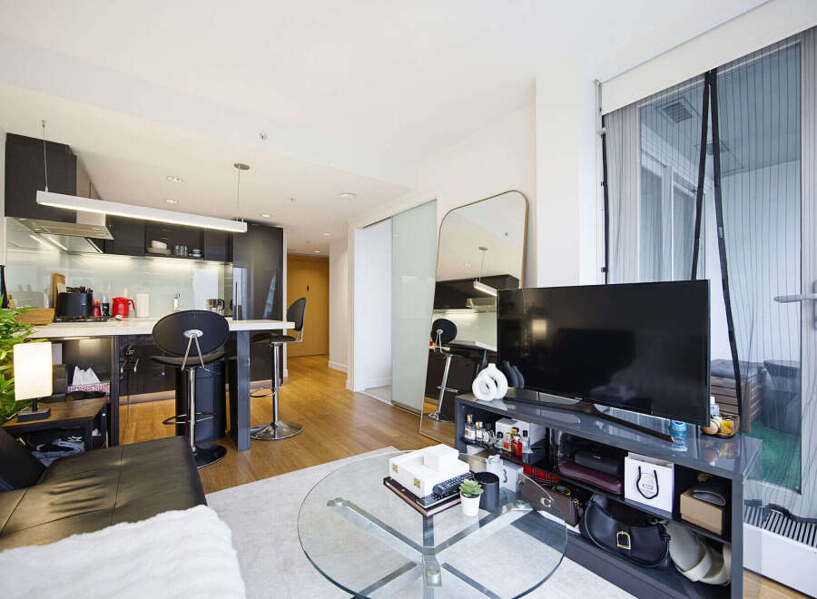 Experience modern urban living in this stylish apartment featuring a sleek, open-plan kitchen with a breakfast bar and contemporary cabinetry.