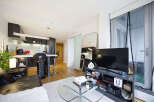 Experience modern urban living in this stylish apartment featuring a sleek, open-plan kitchen with a breakfast bar and contemporary cabinetry.