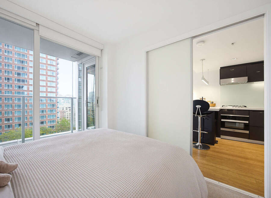 Experience modern urban living in this bright bedroom featuring a comfortable bed and direct access to a private balcony with stunning city views.