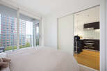 Experience modern urban living in this bright bedroom featuring a comfortable bed and direct access to a private balcony with stunning city views.