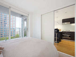Experience modern urban living in this bright bedroom featuring a comfortable bed and direct access to a private balcony with stunning city views.