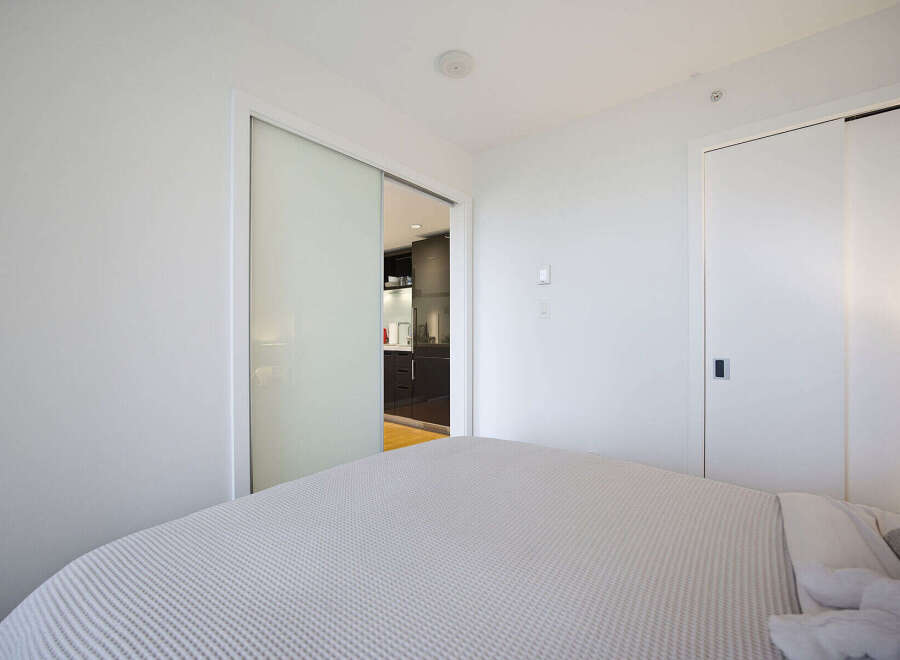 Experience modern living in this bright bedroom featuring a comfortable bed with a textured comforter.