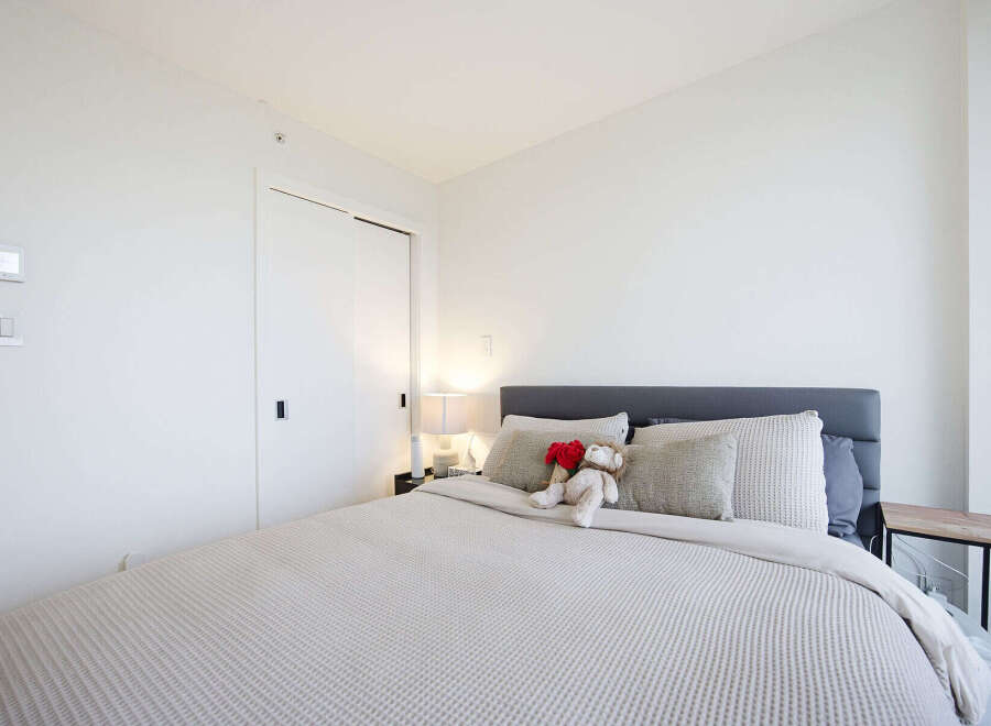Experience modern comfort in this beautifully appointed bedroom, featuring a plush king-sized bed adorned with decorative pillows and a charming teddy bear.