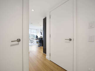Step into this modern apartment hallway, featuring sleek white doors with brushed nickel hardware.