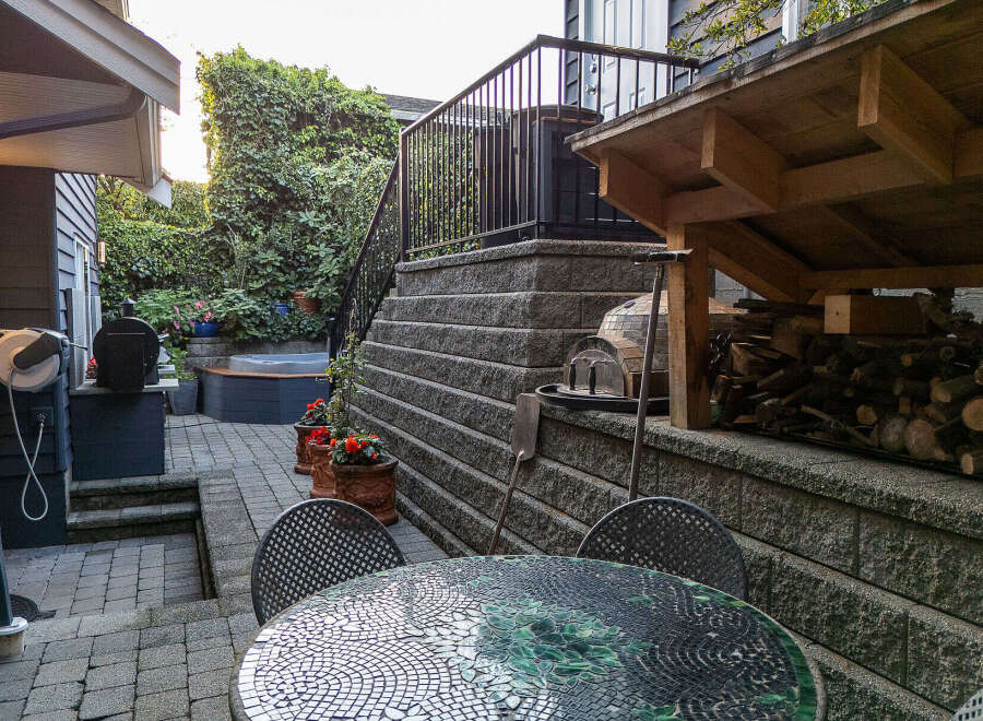 Enjoy outdoor living with this charming backyard featuring a relaxing hot tub surrounded by lush greenery.