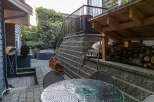 Enjoy outdoor living with this charming backyard featuring a relaxing hot tub surrounded by lush greenery.