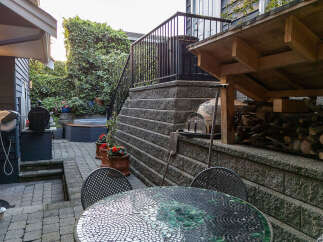 Enjoy outdoor living with this charming backyard featuring a relaxing hot tub surrounded by lush greenery.