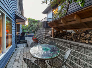 Enjoy outdoor living in this charming backyard featuring a mosaic dining set perfect for al fresco meals.
