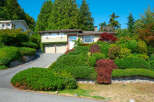 This charming home features a beautifully landscaped hillside with a variety of lush greenery and mature trees, creating a private and serene atmosphere.