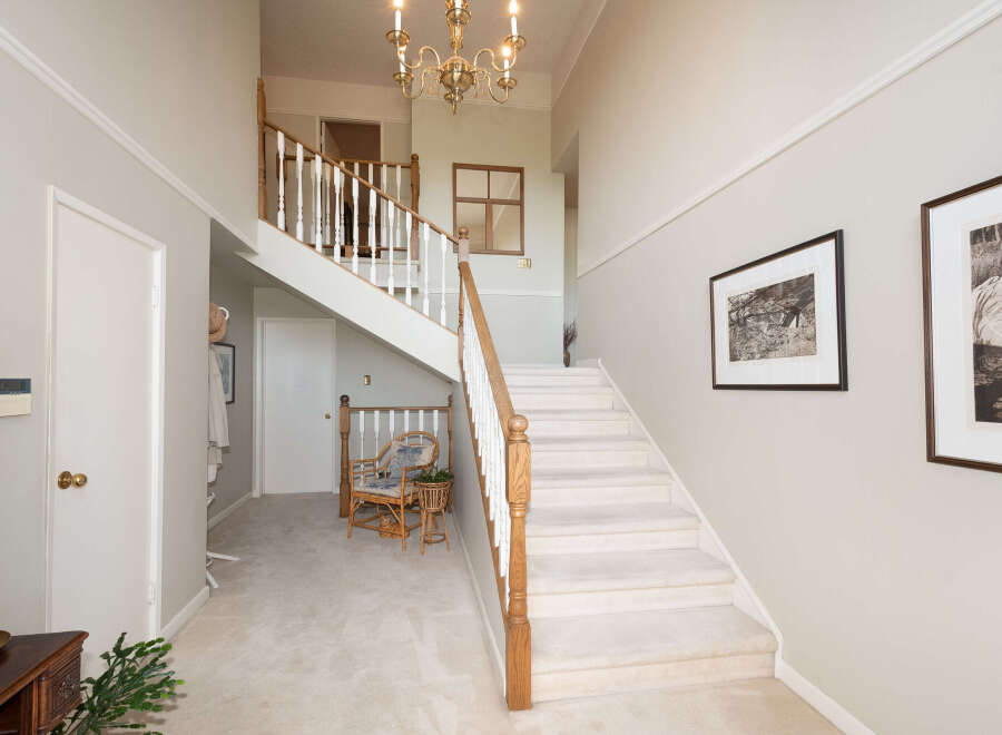 Step into this grand foyer featuring a sweeping staircase with elegant wooden banisters and plush carpeting.