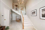 Step into this grand foyer featuring a sweeping staircase with elegant wooden banisters and plush carpeting.