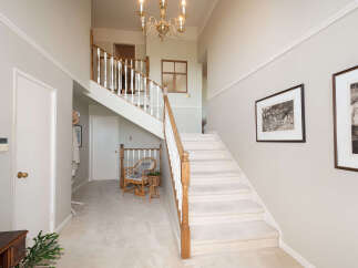 Step into this grand foyer featuring a sweeping staircase with elegant wooden banisters and plush carpeting.