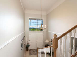 Step into a grand foyer featuring a stunning chandelier and a large window offering picturesque views.