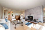 This inviting living room features a large, whitewashed brick fireplace as the focal point, complemented by comfortable seating arrangements.