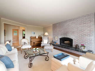 This inviting living room features a large, whitewashed brick fireplace as the focal point, complemented by comfortable seating arrangements.