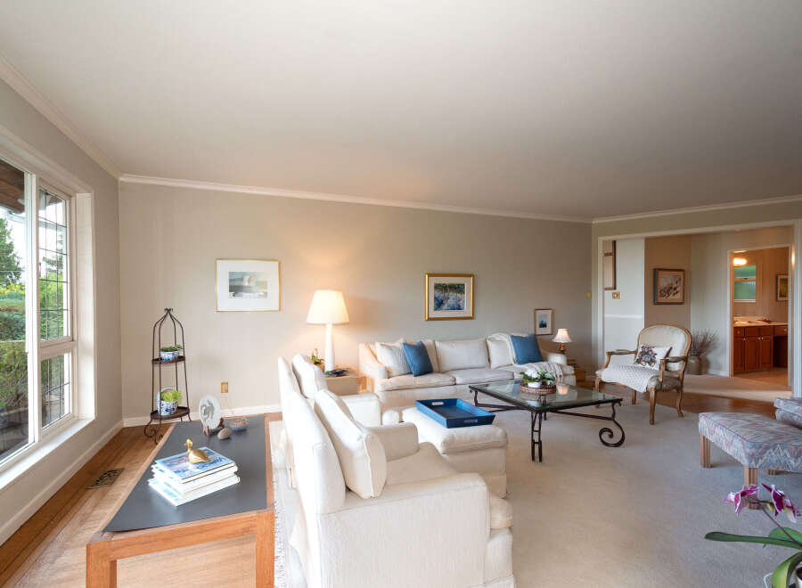 Step into this inviting living room, bathed in natural light from a large bay window overlooking lush greenery.