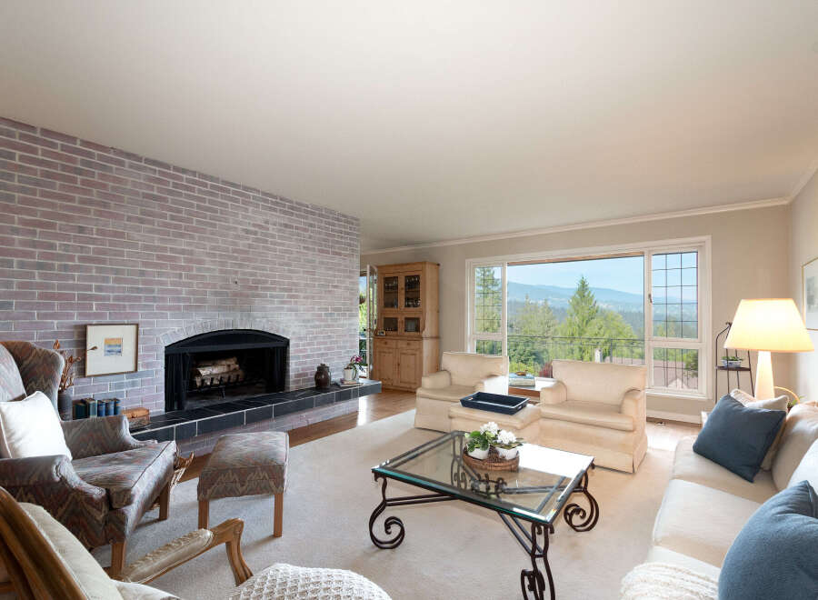 Experience breathtaking panoramic views from this stunning living room, featuring a cozy brick fireplace and ample natural light.