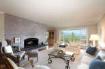 Experience breathtaking panoramic views from this stunning living room, featuring a cozy brick fireplace and ample natural light.