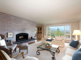 Experience breathtaking panoramic views from this stunning living room, featuring a cozy brick fireplace and ample natural light.